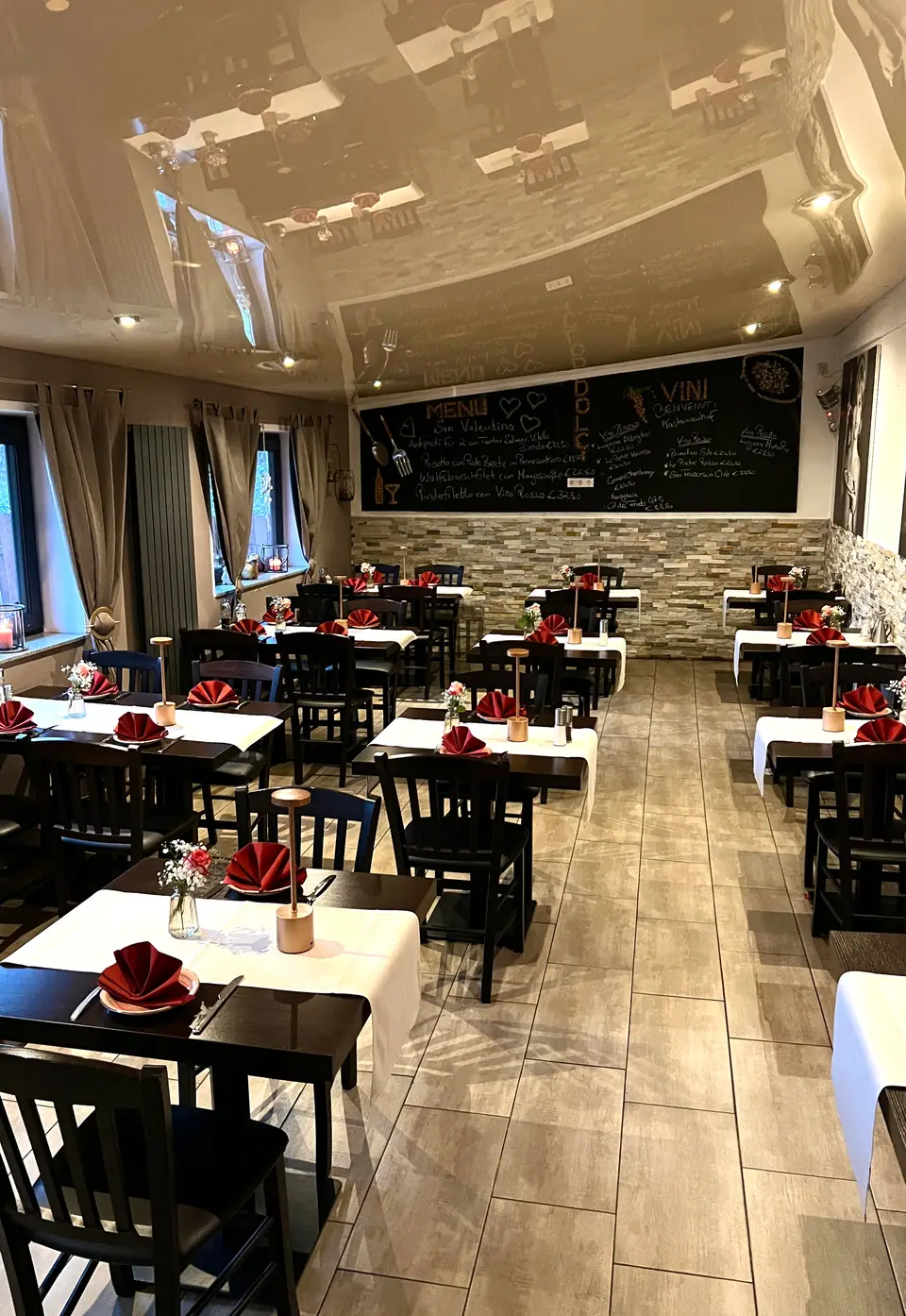 Gastraum des italienischen Restaurants Kastanienhof in Moers mit gedeckten Tischen und Natursteinwand