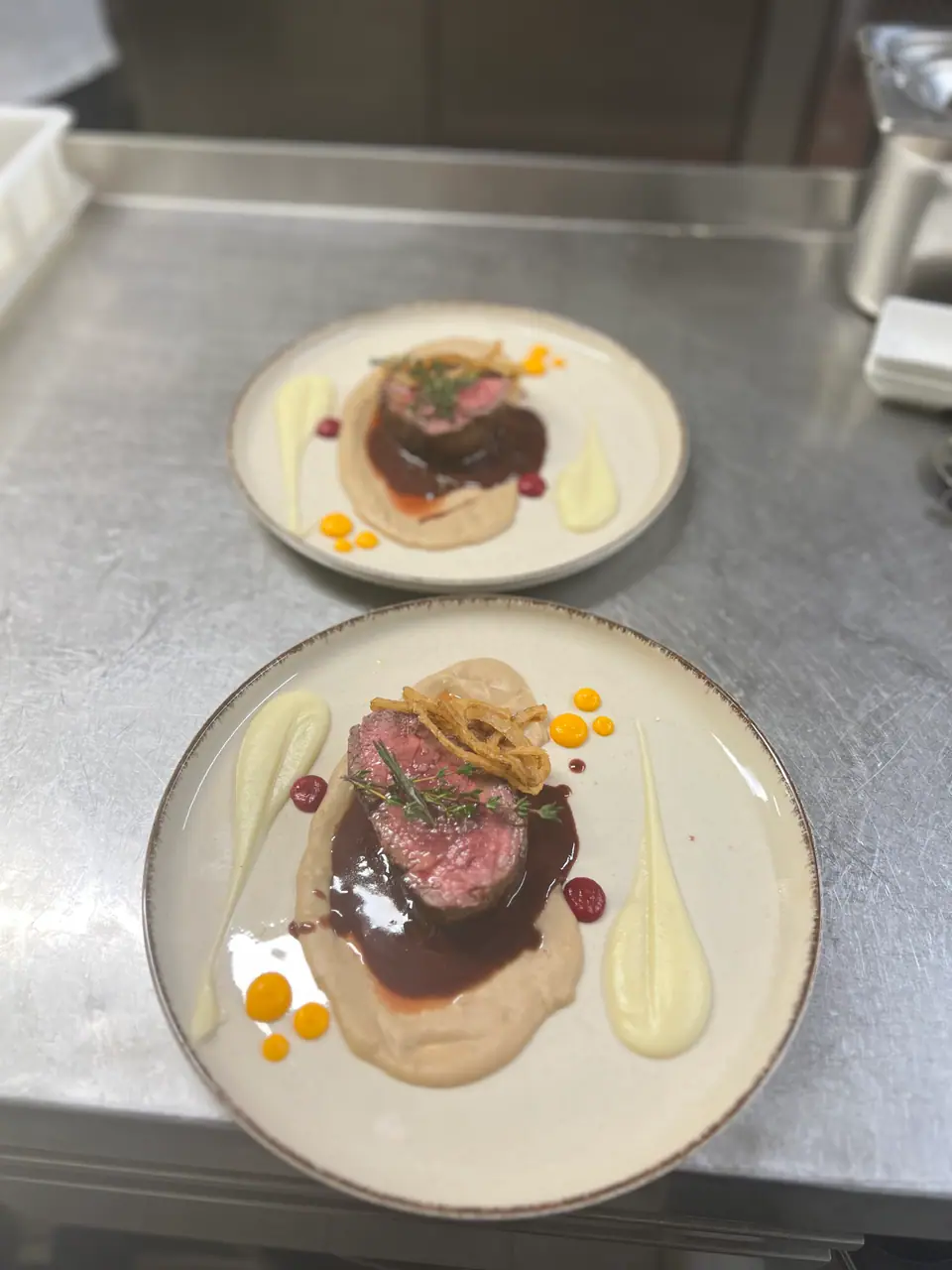 Zwei Teller mit rosa gebratenem Rindfleisch, Sauce und Püree